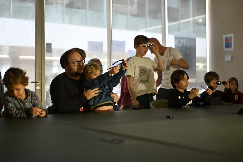 People wearing polarised goggles, are looking at a lightsource from the far end of a table towards the photographer. They are vitising the open dy of SRON